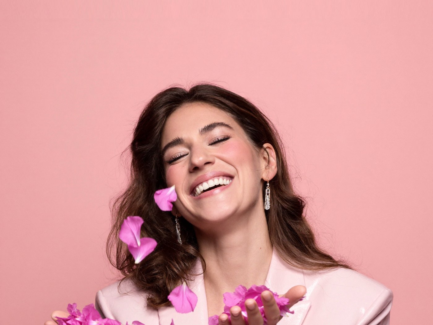 Mujer sonriendo mientras lanza pétalos de flores